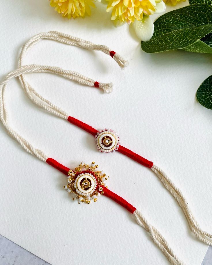 two red and white necklaces sitting next to flowers