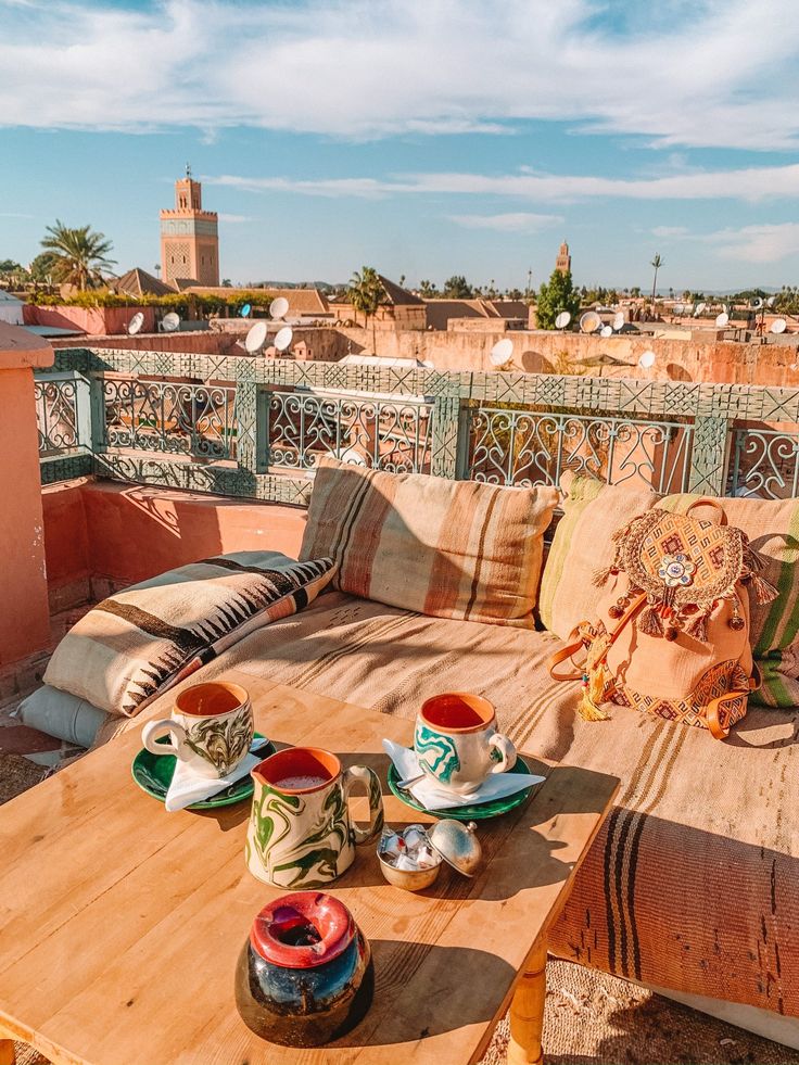 a wooden table topped with two cups and saucers on top of a patio next to a balcony