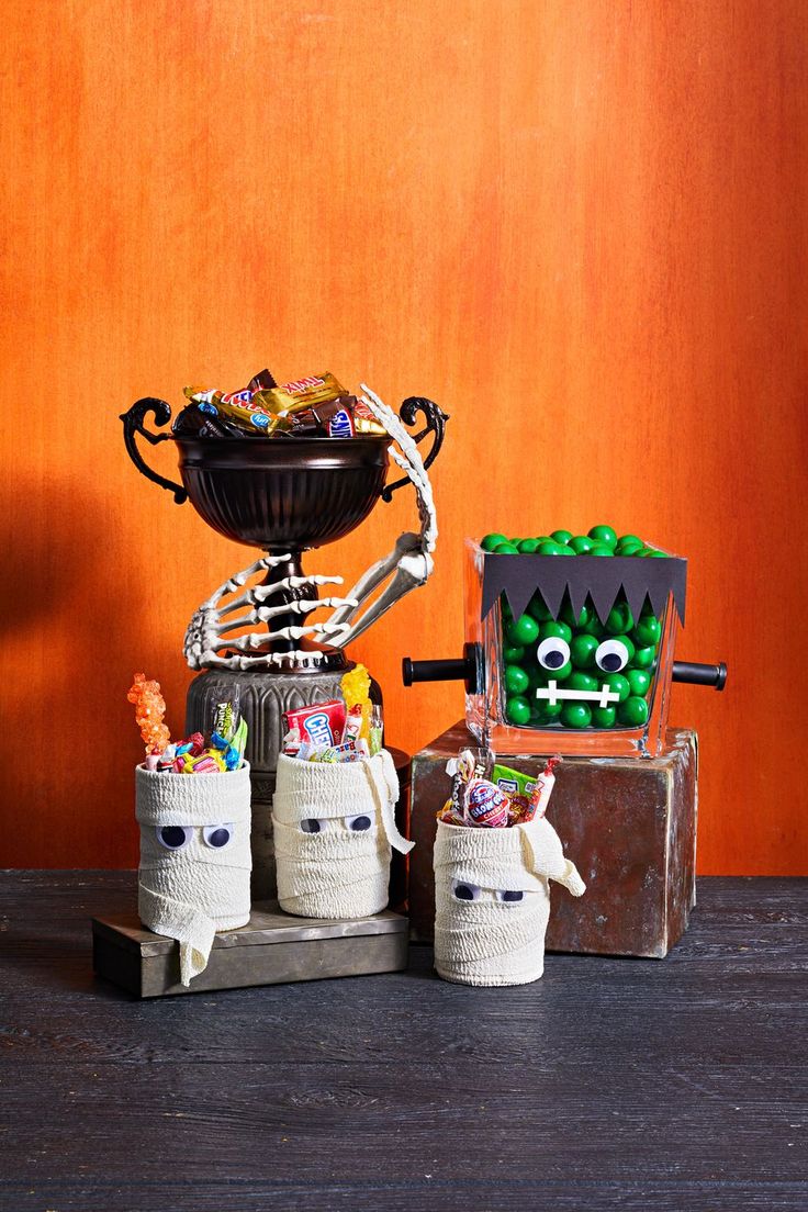 halloween decorations made out of toilet rolls and candy in front of a wooden wall with an orange background