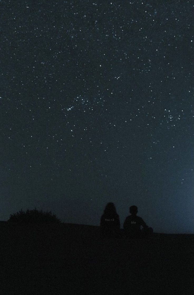 two people sitting under the stars in the night sky