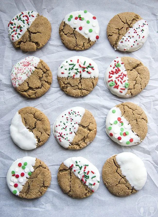 twelve cookies with white frosting and sprinkles on a sheet of paper