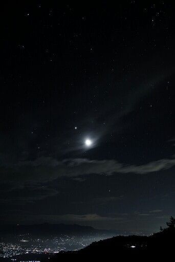 the night sky is full of stars and bright lights, as seen from a hill