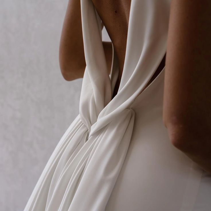 the back of a woman's white dress, with her hand on her shoulder