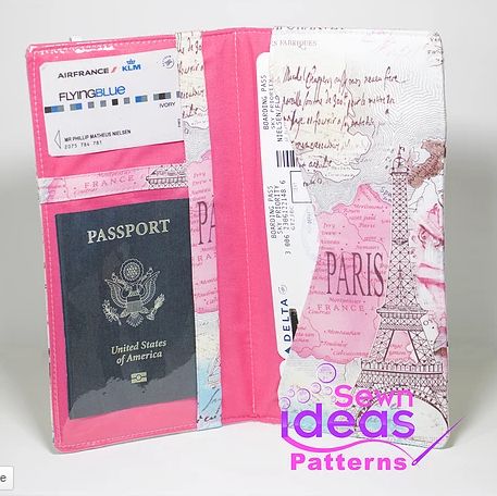 an open passport case with pink paper and travel tags on it's front pocket