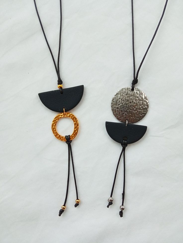 two necklaces are hanging on a white sheet and one is gold, the other is black