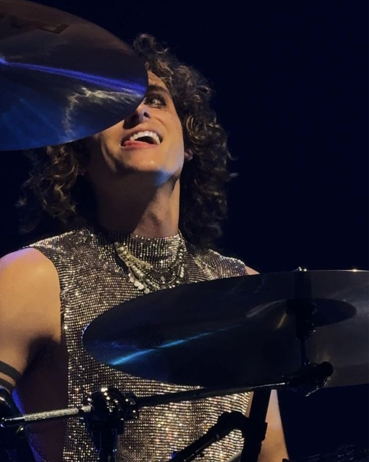 a woman with curly hair is playing the drums