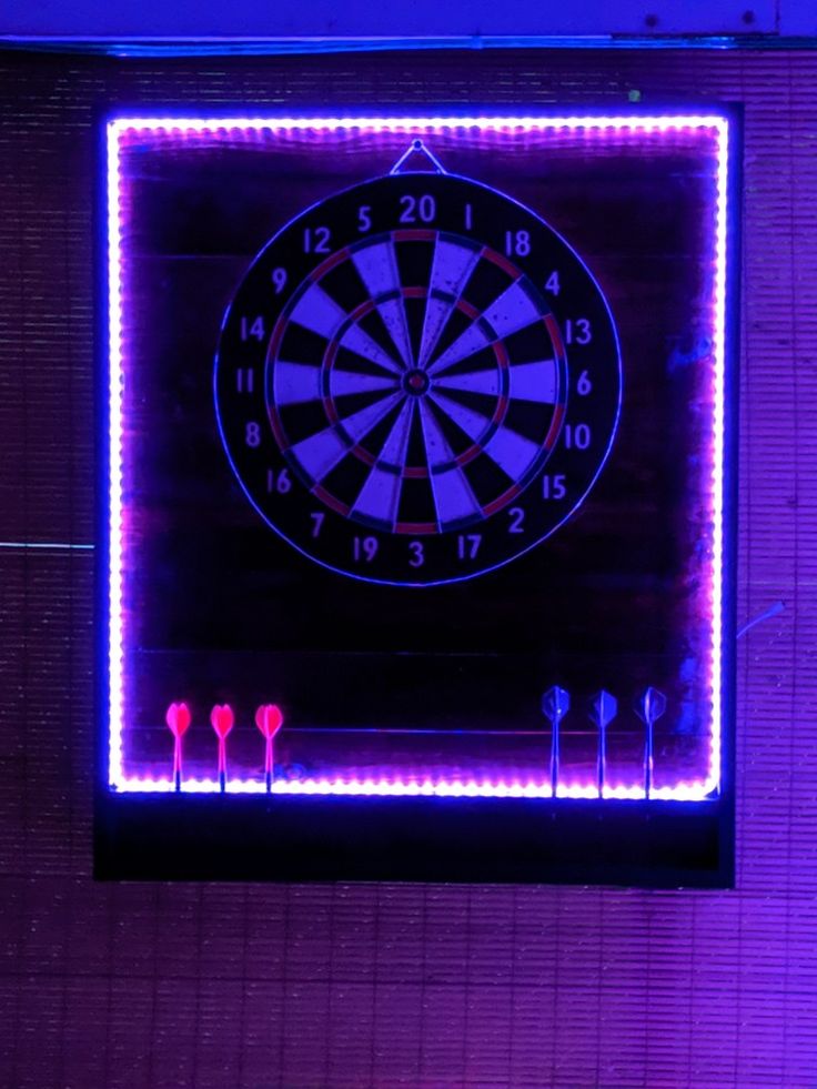 a dart board with neon lights on the wall and behind it is a purple light