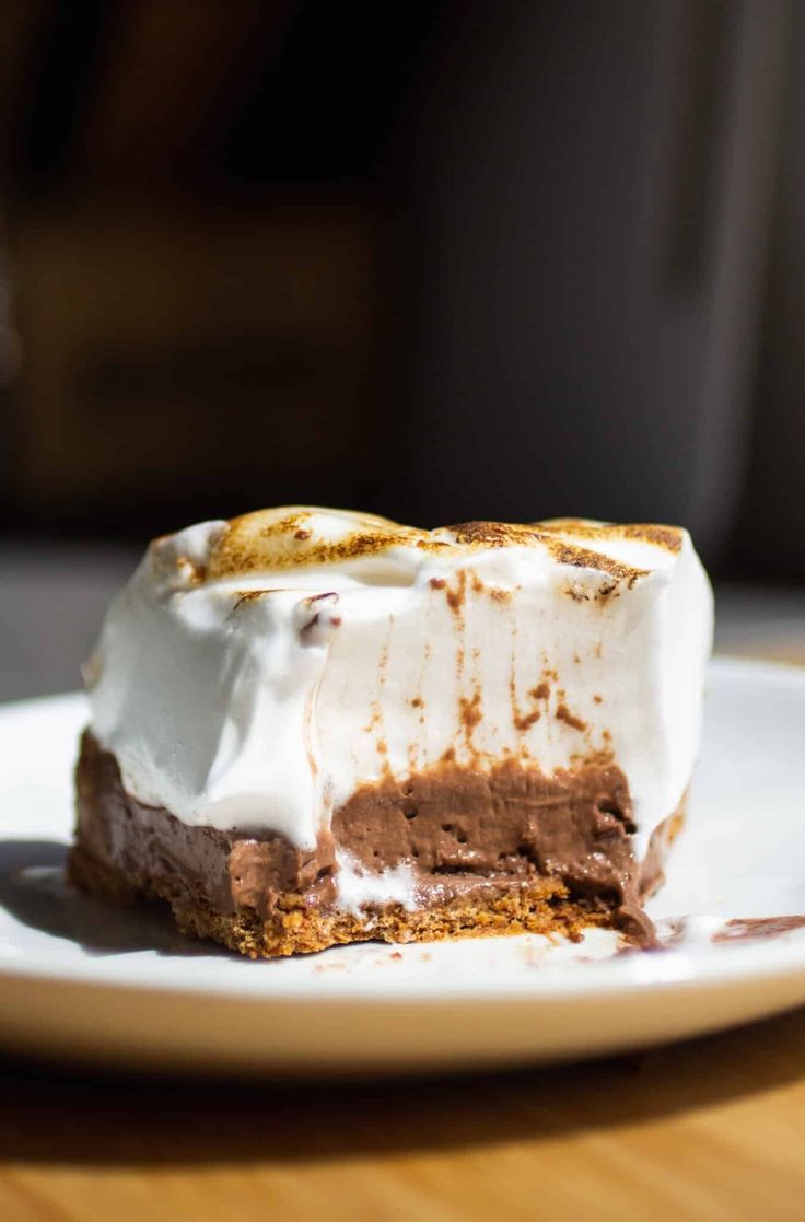 a piece of cake sitting on top of a white plate covered in whipped cream and chocolate