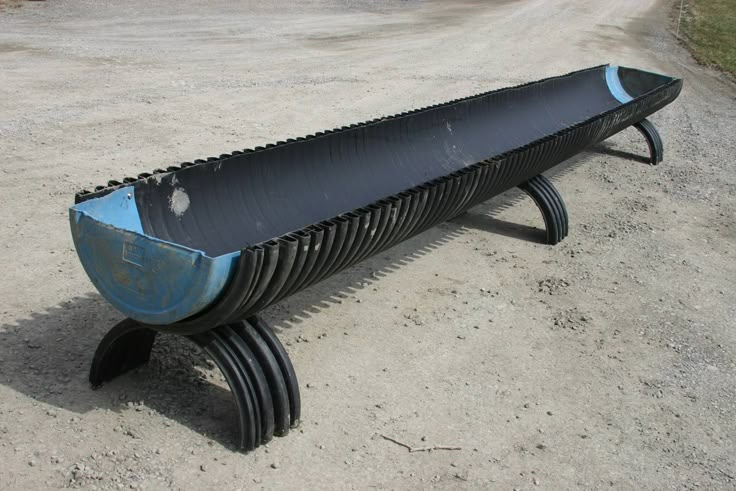 a black and blue bench sitting on top of a dirt road next to a field