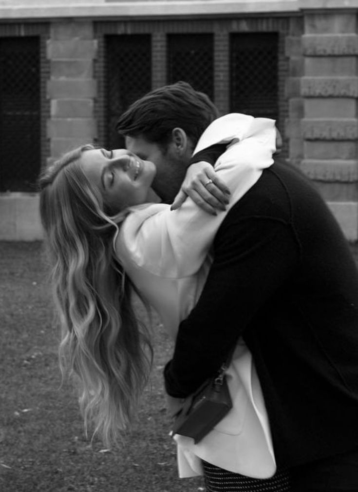 a man and woman kissing in front of a building