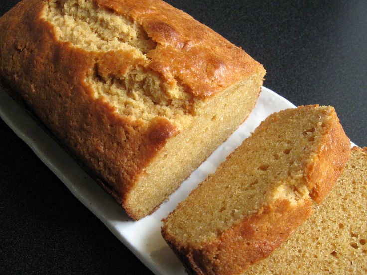 a loaf of bread sitting on top of a white plate next to a slice of cake