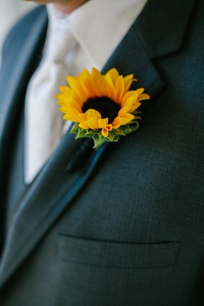 a man in a suit with a sunflower boutonniere on his lapel