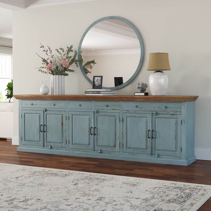 a room with a rug, mirror and blue cabinet