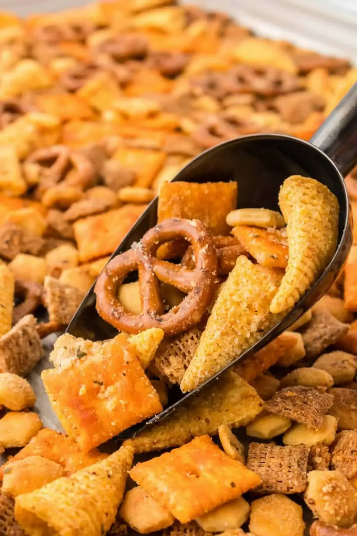 a spoon filled with cheetos and pretzels on top of a pile of cereal