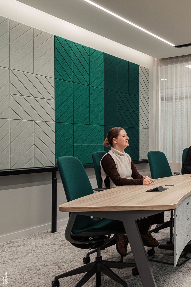 two people sitting at a table in an office setting with green and white wallpaper