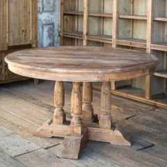 an old wooden table sitting on top of a hard wood floor next to bookshelves