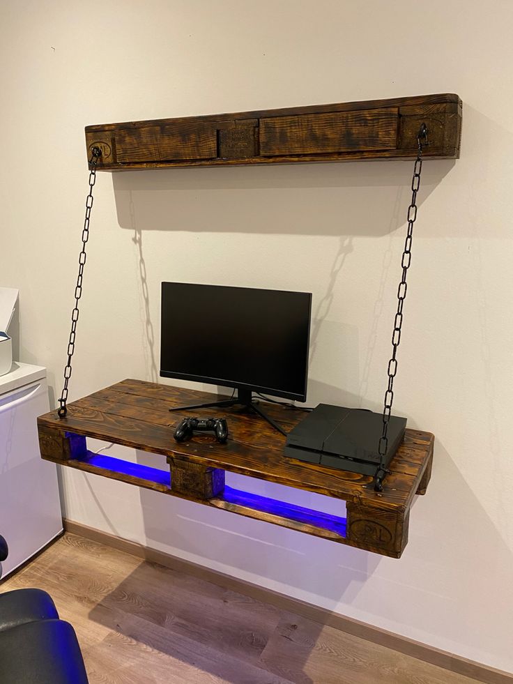 a desk with a monitor, keyboard and mouse on it in a room that has white walls