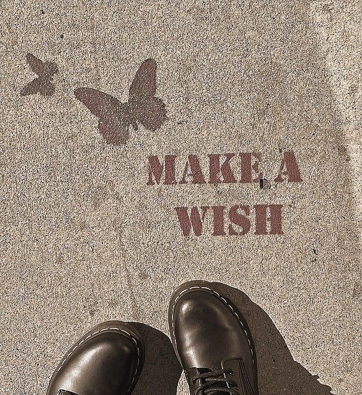 a pair of shoes standing in front of a sidewalk with the words make a wish painted on it