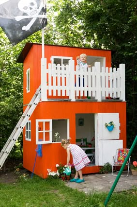 a child's play house with a pirate flag on the roof and stairs to the second floor