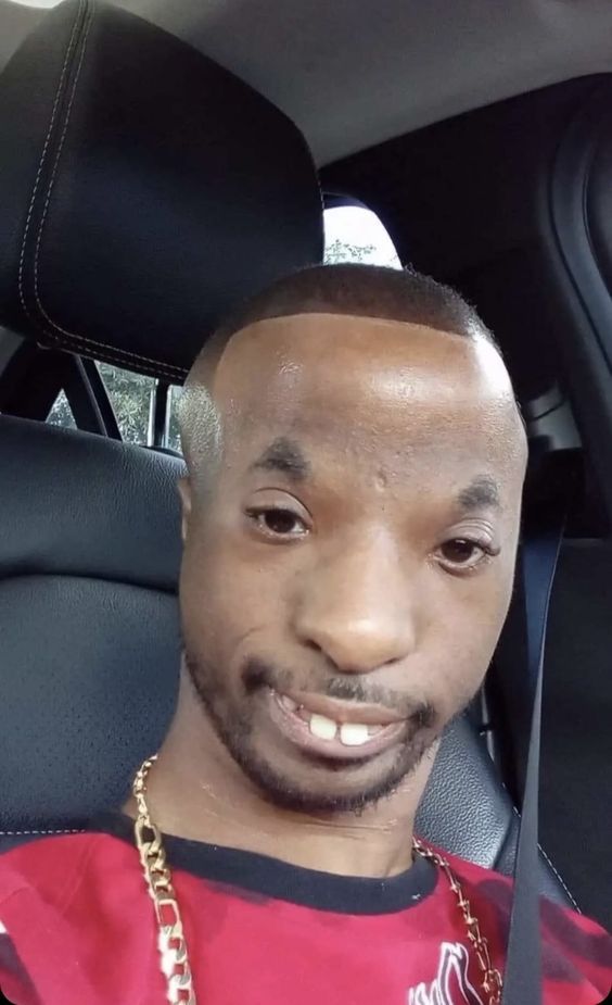 a man sitting in the back seat of a car wearing a gold chain around his neck