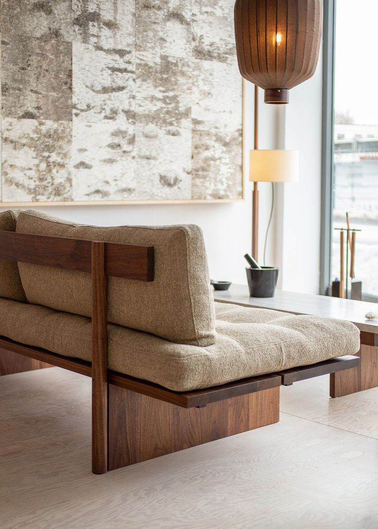 a couch sitting on top of a wooden floor next to a window with a painting hanging above it