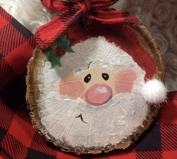 a christmas ornament with a santa clause on it's face is hanging from a red and black checkered tablecloth