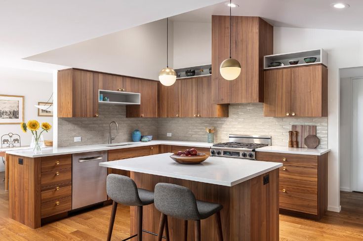 a kitchen with wooden cabinets and white counter tops, two stools are in front of the center island