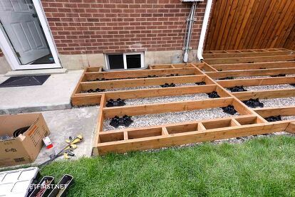 an outdoor patio being built with wooden pallets in the grass next to a brick building