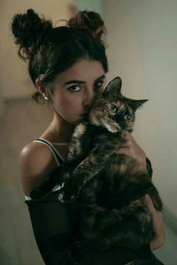 a woman holding a cat in her arms and looking at the camera with an intense look on her face