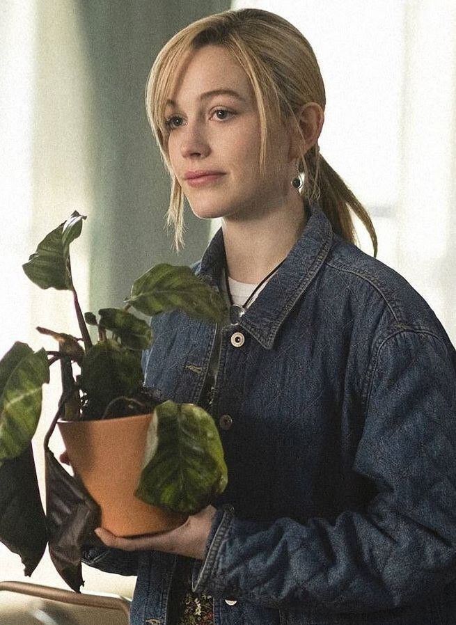 a woman is holding a potted plant in her hand and looking at the camera