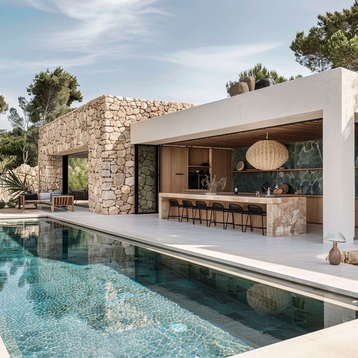 an outdoor kitchen next to a pool in the middle of a house with stone walls