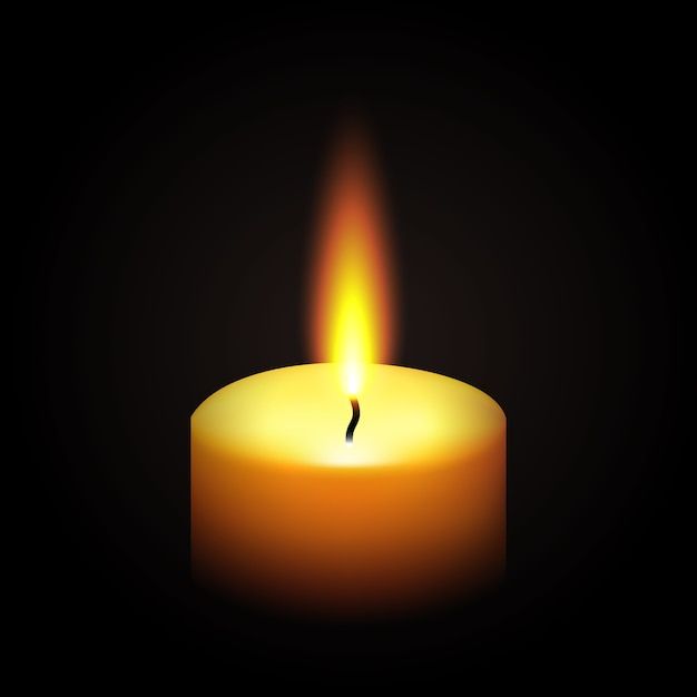 a lit candle in the dark on a black background