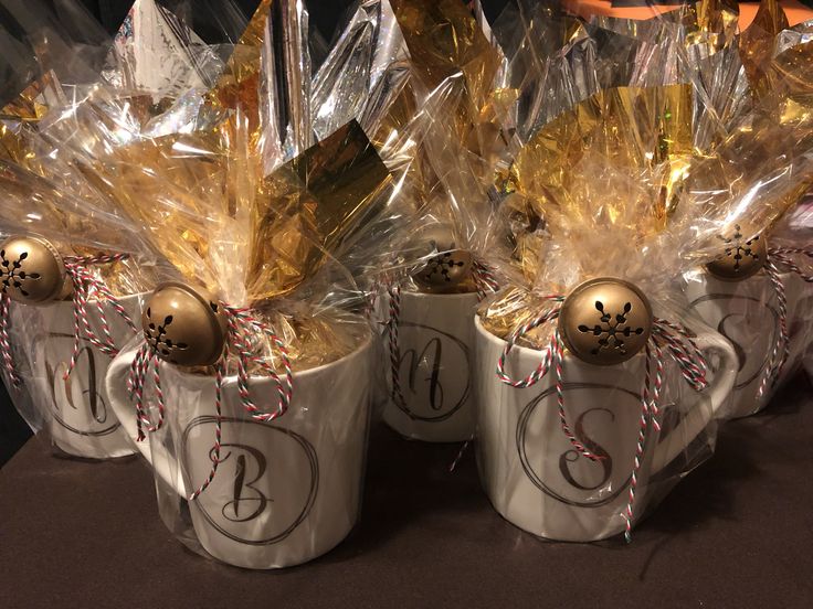 three coffee mugs decorated with gold and silver christmas balls, wrapped in cellophane