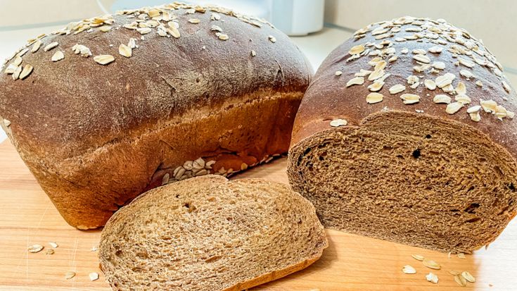 two loaves of bread sitting on top of a cutting board next to a loaf of bread