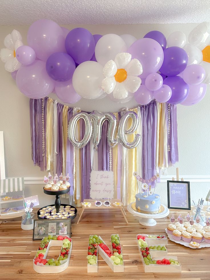 a table topped with lots of balloons and desserts next to a sign that says love