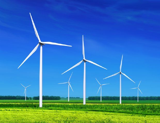 several wind turbines are shown in the middle of an open field with green grass and blue sky