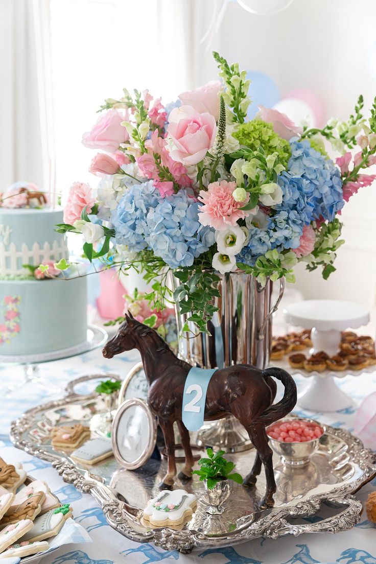 a table topped with a vase filled with flowers next to a horse figurine