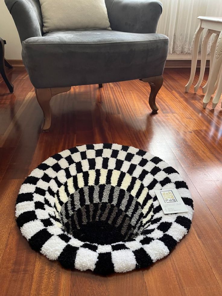 a black and white basket sitting on top of a wooden floor next to a chair