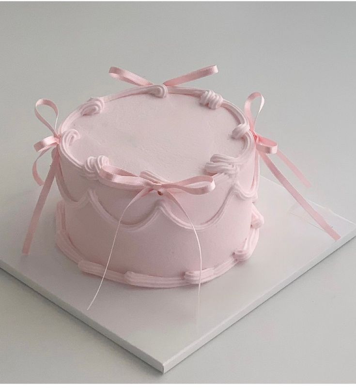 there is a pink cake with ribbons on it