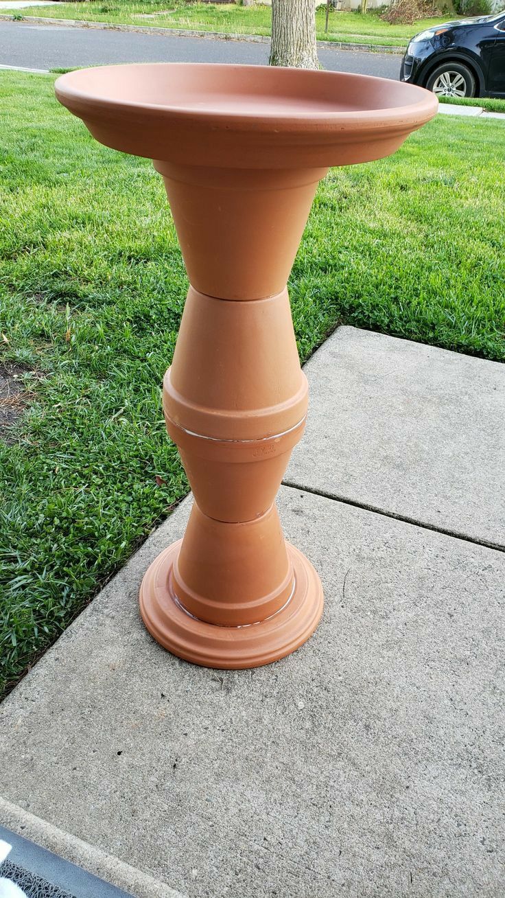 a planter sitting on the side of a sidewalk in front of a grass field