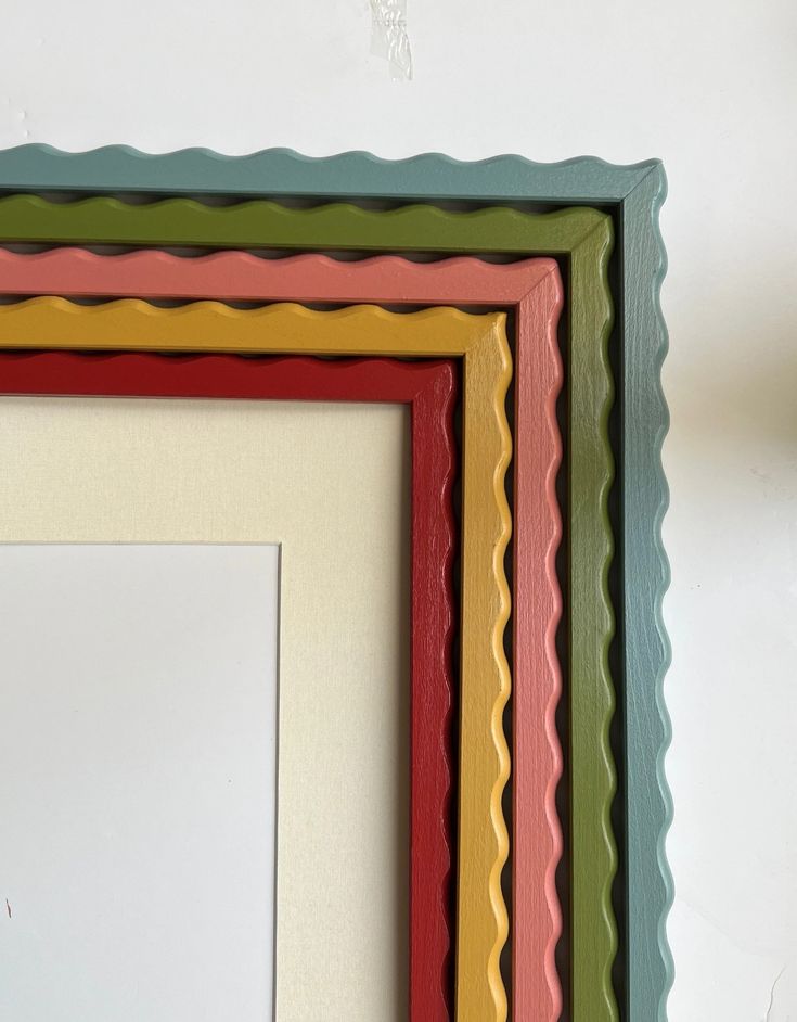 three different colored frames hanging on the wall with one empty piece of paper in front of them