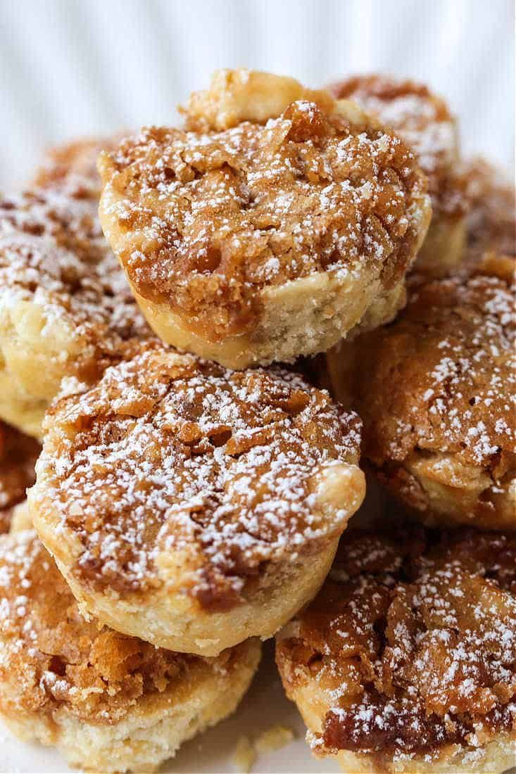 a pile of powdered sugar donuts sitting on top of a white plate