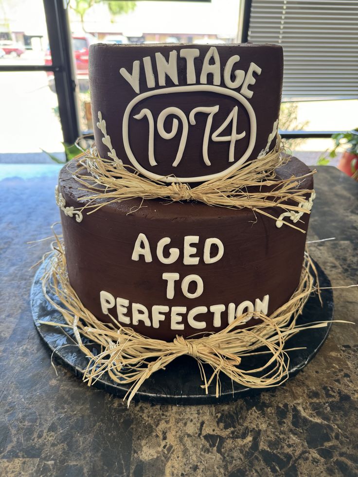 a three tiered cake with the words aged to perfection written on it and straw