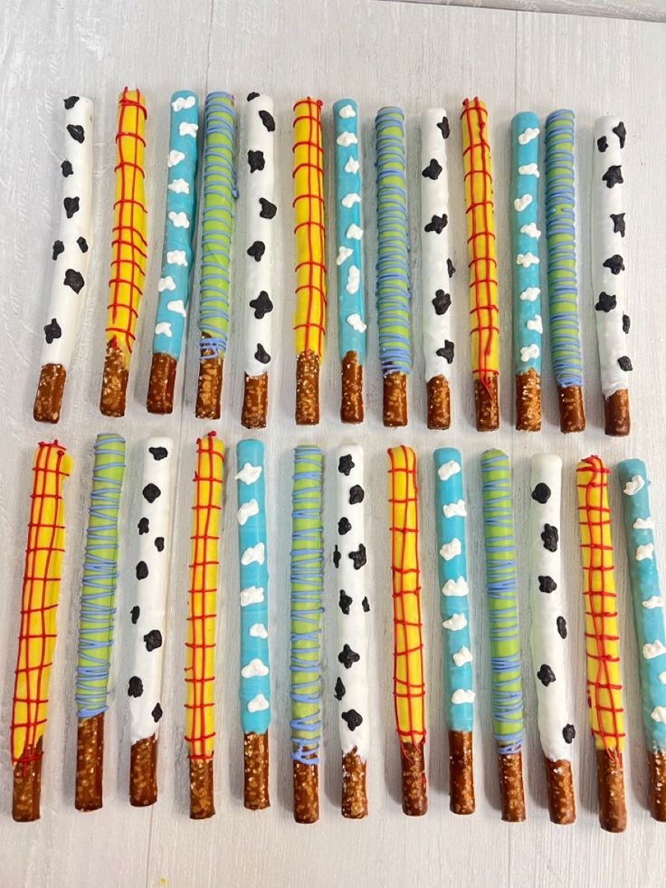 many different types of candy sticks are arranged on a white tablecloth with black and yellow designs