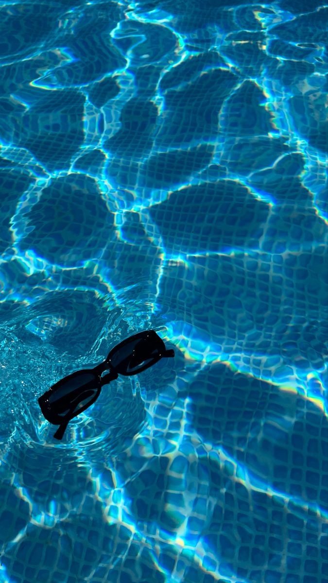 a pair of swimming goggles floating on top of the blue water in a pool