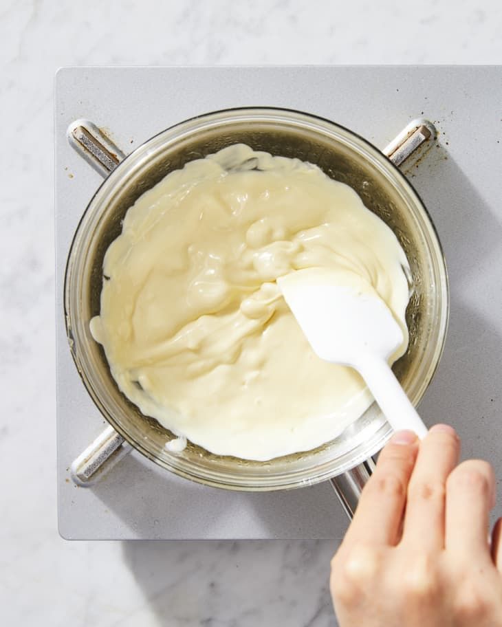 a person mixing cream in a pot on the stove