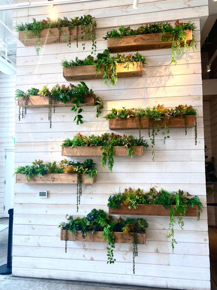 several wooden planters are arranged on the wall with plants growing in them and hanging from hooks