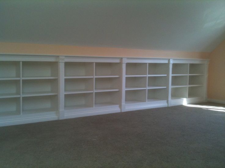 an empty room with white bookcases and carpet