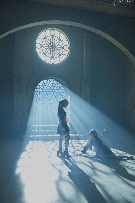 two people standing in front of a window with sunlight coming through the window and casting shadows on the floor