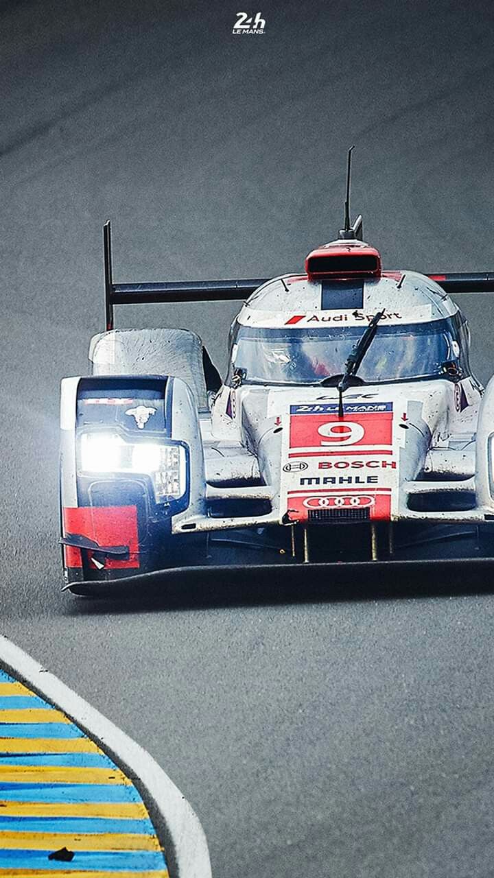 a racing car driving down a race track with the lights on in front of it